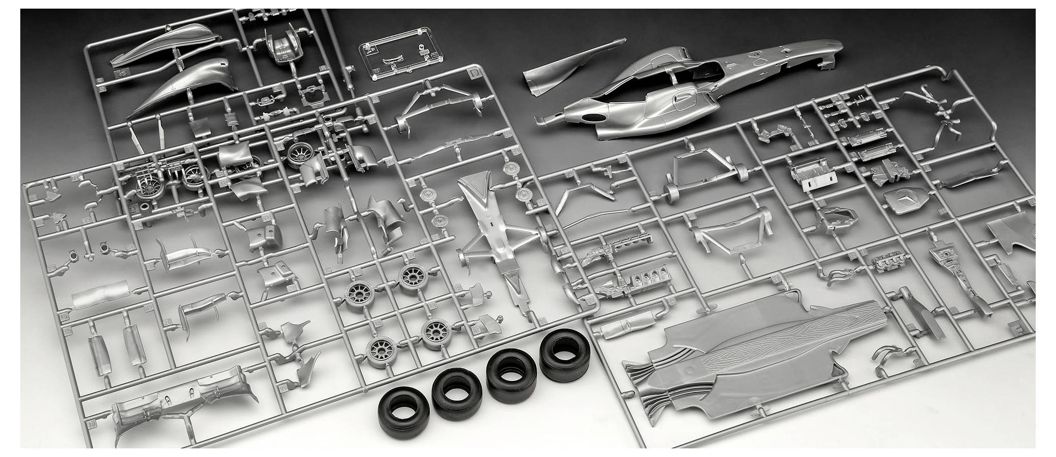 Plastikmodell-Bausatzteile, die auf Angüssen angeordnet sind, mit Fahrzeugkarosserie, Rädern und verschiedenen Teilen, die zur Montage bereitliegen.