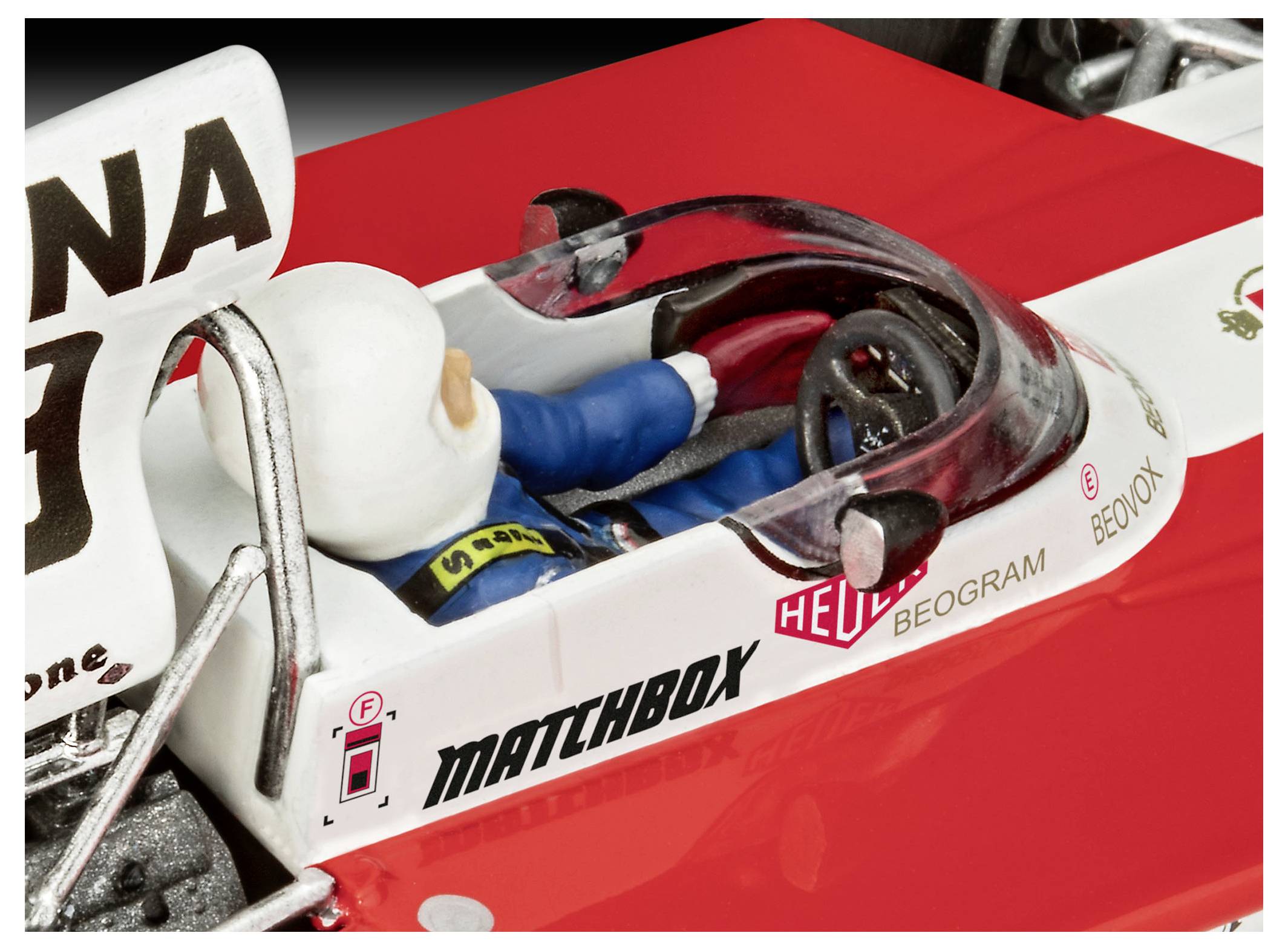 Eine Nahaufnahme eines Spielzeug-Rennfahrers in einem rot-weißen Auto. Der Fahrer trägt einen blauen Anzug und einen weißen Helm und sitzt im Cockpit.