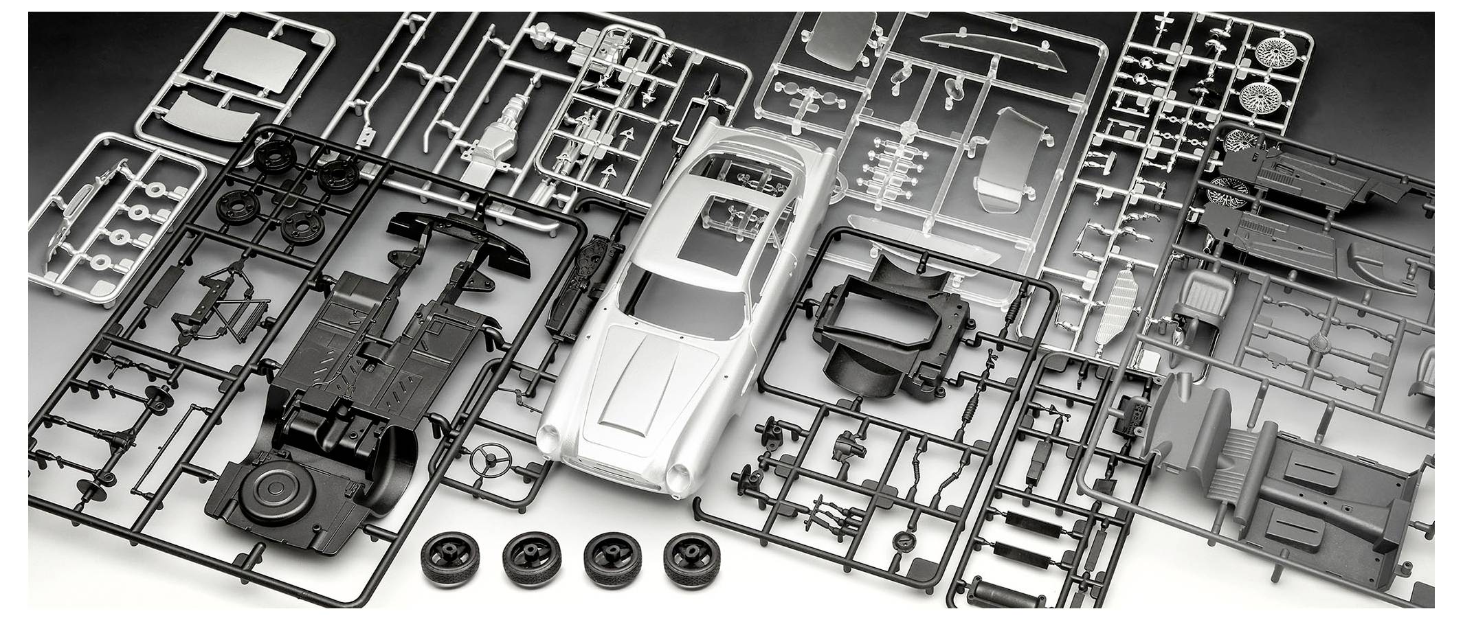 Ein Modell-Autobausatz, der mit verschiedenen Kunststoffteilen und Reifen ausgelegt ist, fertig zur Montage.
