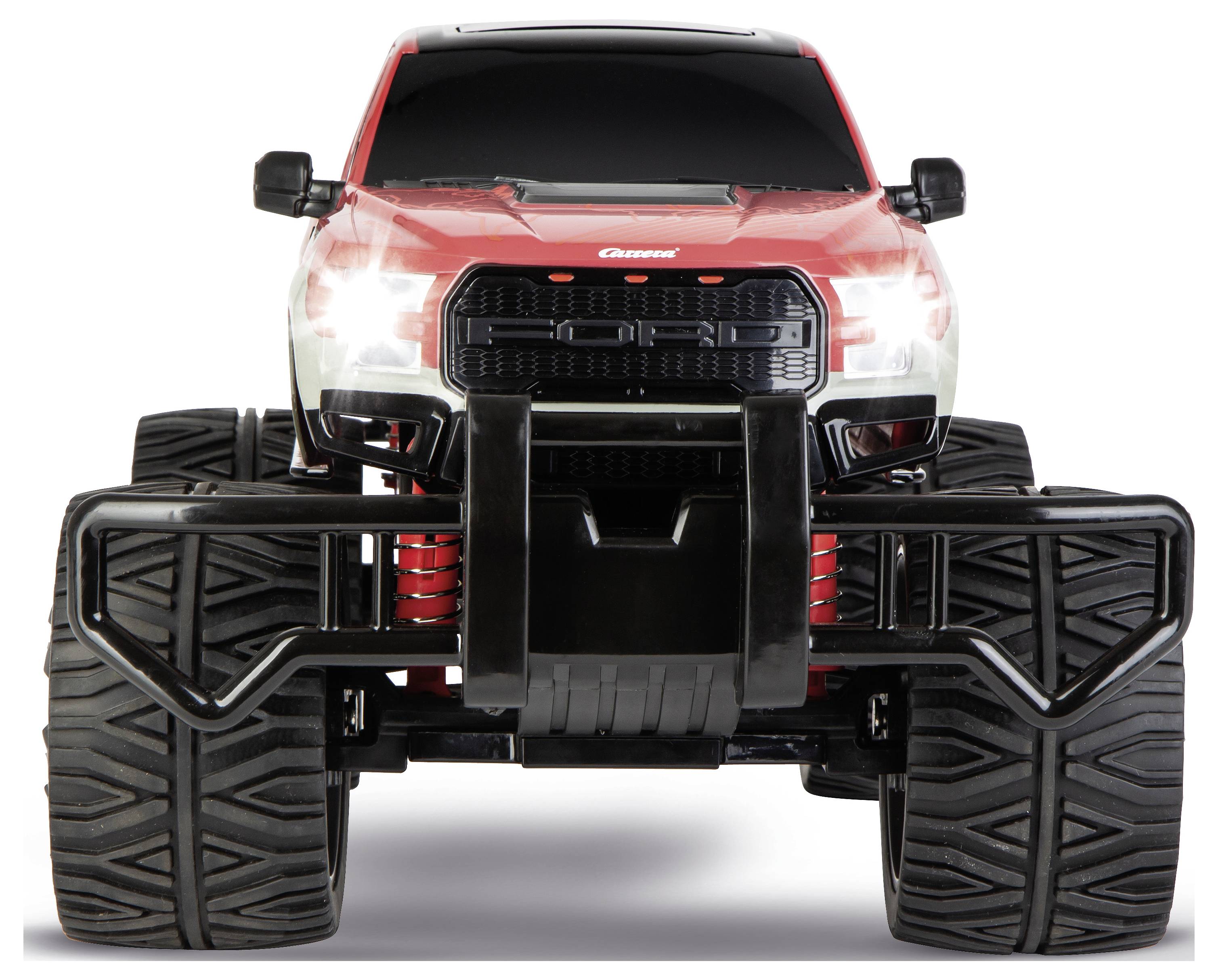 Ein rotes und schwarzes Spielzeug-Monstertruck mit großen Reifen und erhöhter Federung, von vorne gezeigt, wobei sein robustes Design betont wird.