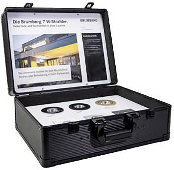 Ein offener schwarzer Koffer zeigt drei verschiedene Leuchten in der unteren Hälfte und eine Broschüre mit Bildern und Text über Beleuchtung in der oberen Hälfte.