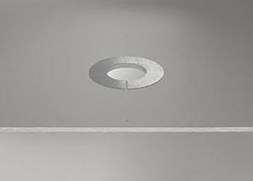 Ein kreisförmiger metallischer Ring, der in eine glatte graue Oberfläche eingebettet ist, in einem minimalistischen Design.