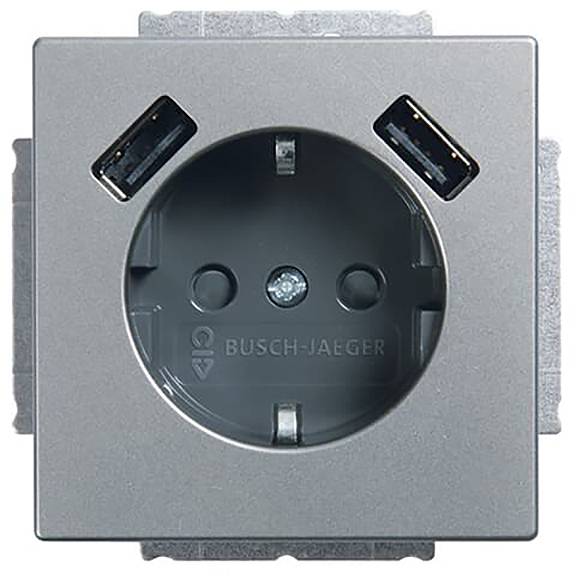 Eine Wandsteckdose mit einer europäischen Steckdose und zwei USB-Anschlüssen in den oberen Ecken. Die Marke „Busch-Jaeger