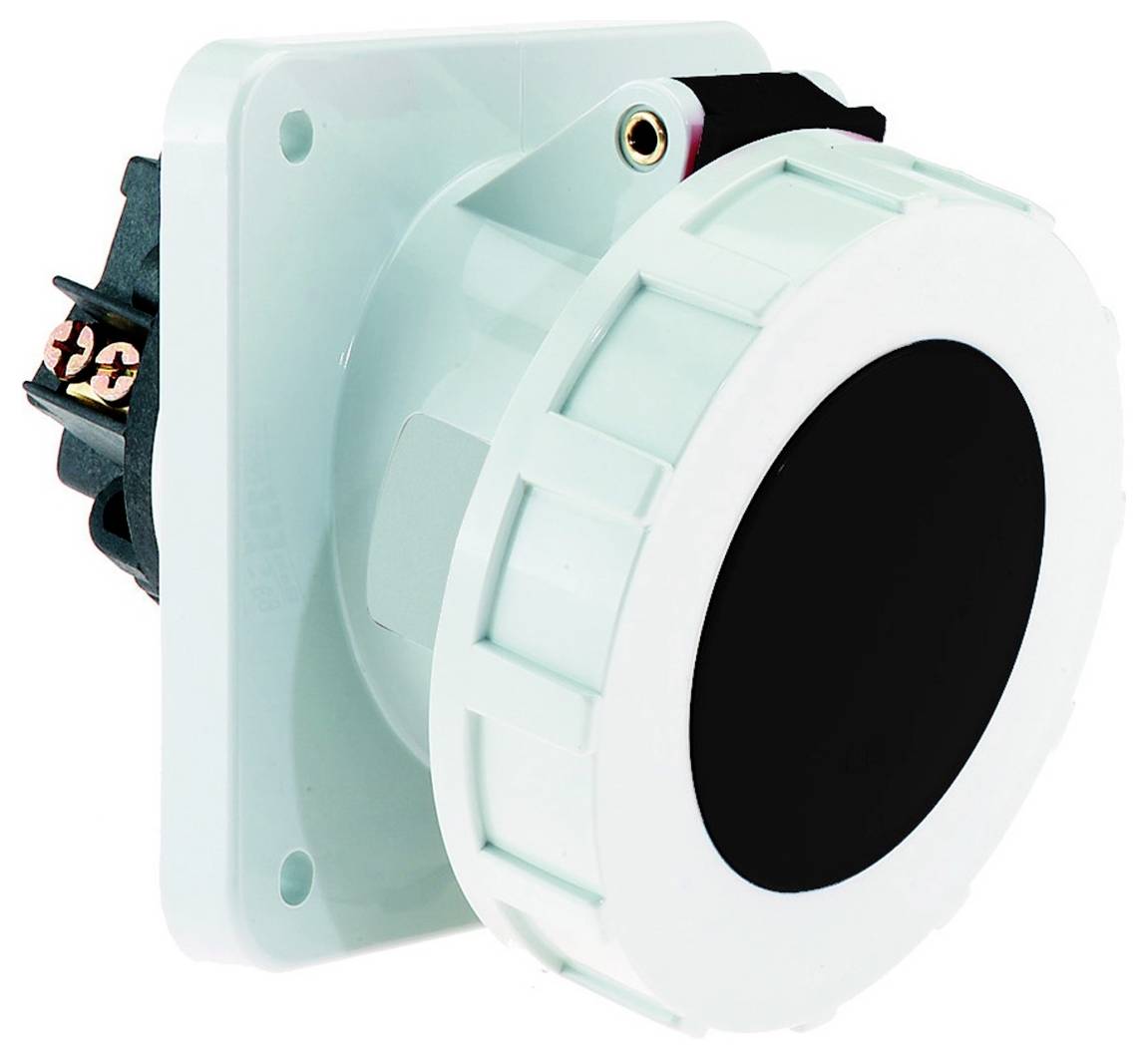 Ein großer kreisförmiger Industrieschalter mit schwarzer Mitte und weißem Rand, montiert auf einem hellfarbigen Bedienfeld, teilweise sichtbare Verdrahtung.