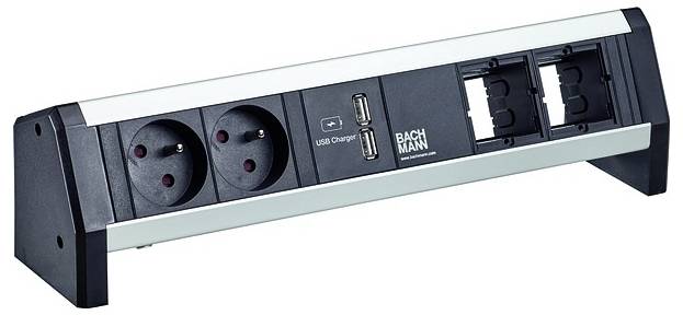 Eine schwarze Steckdosenleiste mit zwei europäischen Steckdosen, zwei USB-Anschlüssen und zwei leeren Plätzen für zusätzliche Module steht auf einem Tisch.