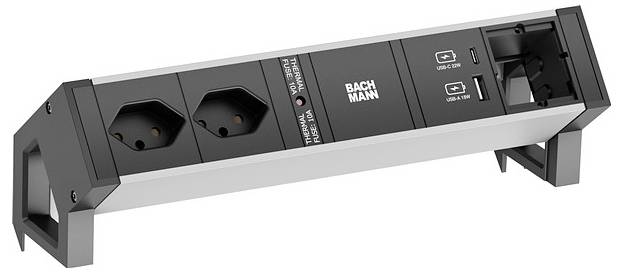 Eine Steckerleiste mit zwei europäischen Steckdosen, zwei USB-Ladeanschlüssen und einem Schalter, mit der Markenbezeichnung „Bachmann