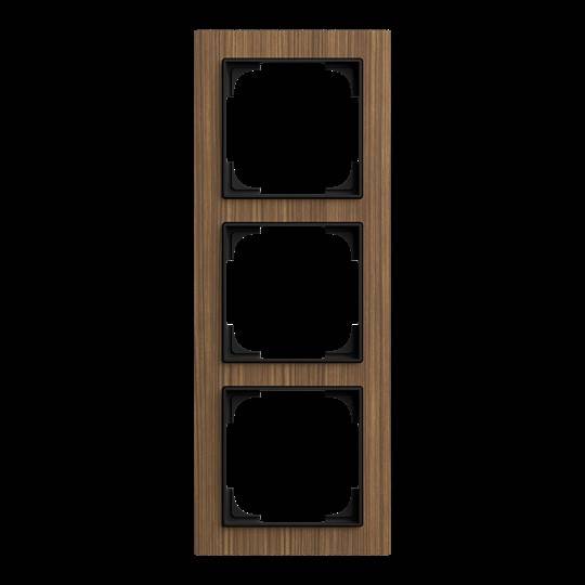 Ein Holz-Dreifach-Lichtschalterrahmen mit drei leeren Schlitzen, die vertikal vor schwarzem Hintergrund angeordnet sind.
