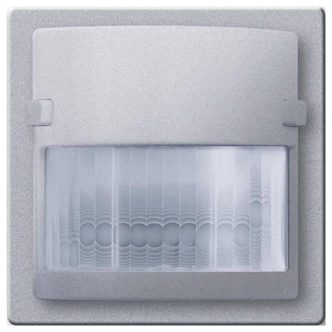 Ein an der Wand montierter Bewegungsmelder mit rechteckigem, silbernem Gehäuse und gebogenem weißem Sensorfeld, konstruiert für die Verwendung im Innenbereich.