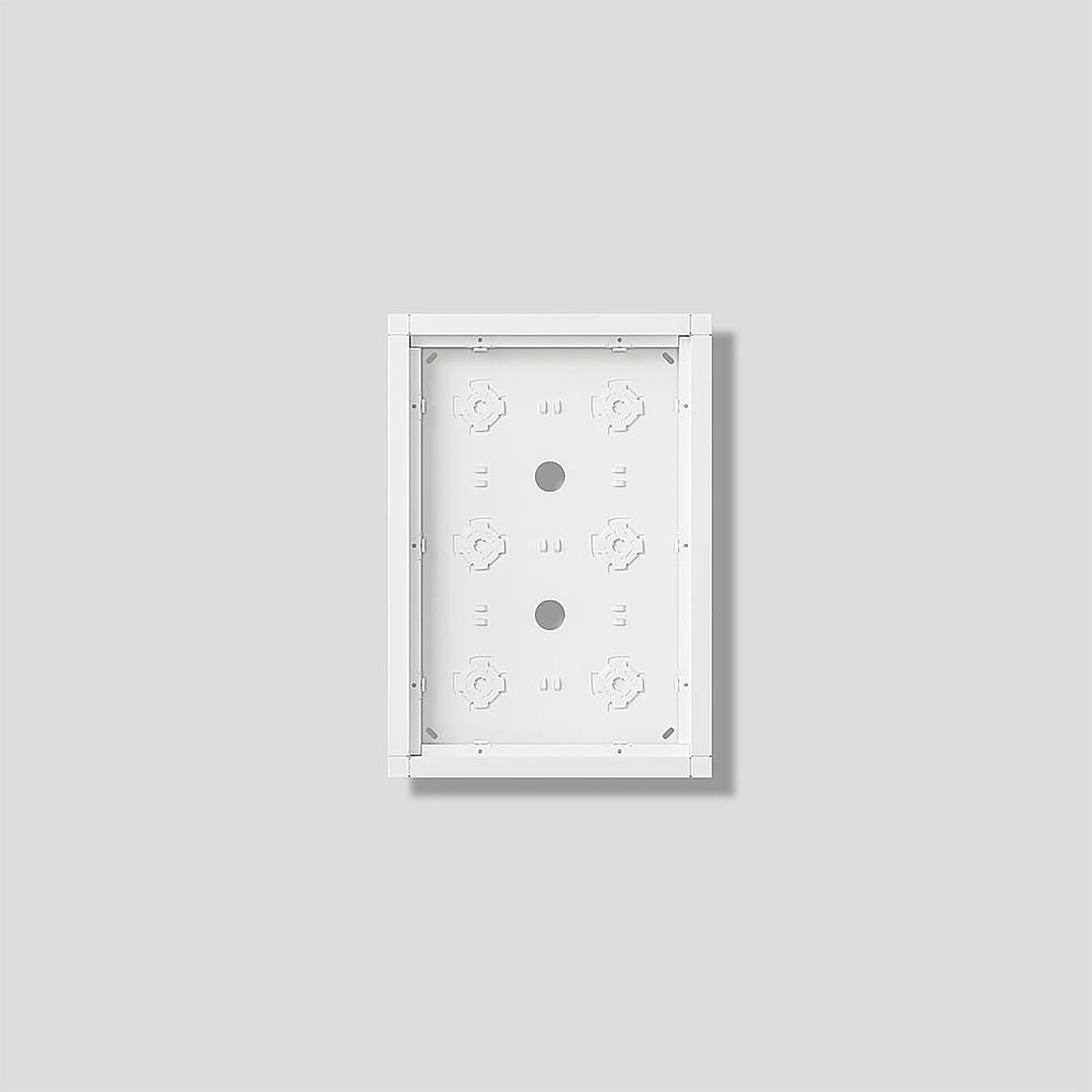 Ein rechteckiges weißes Elektropanel mit kreisförmigen Ausschnitten ist an einer einfachen grauen Wand montiert und zeigt eine Innenansicht mit Montageslitzen.