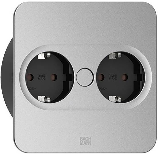 Eine doppelte Steckdose auf einer quadratischen, silbernen Blende. Beide Steckplätze sind mit „Bach Man