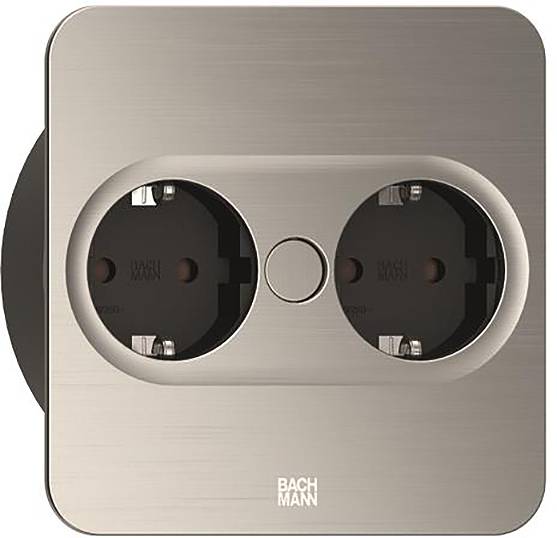 Eine doppelte europäische Wandsteckdose mit metallischer Oberfläche, bestehend aus zwei schwarzen Steckplätzen und einem kreisförmigen Knopf in der Mitte, mit der Marke 'Bachmann'.