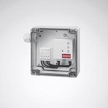 Eine transparente quadratische Elektroverteilerdose mit Drähten, die an eine Klemmleiste angeschlossen sind, und einem kleinen elektronischen Bauteil im Inneren.