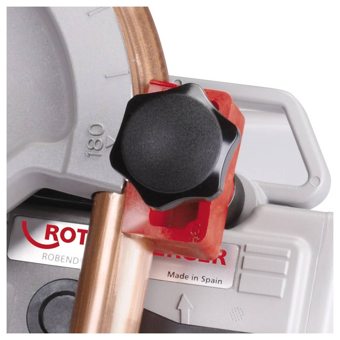 Eine Nahaufnahme eines Rohrabschneiders mit rotem Griff, der eine Kupferrohrleitung umklammert und den Schneidmechanismus zeigt.