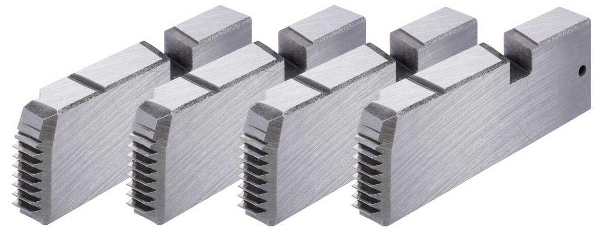 Vier Drehbankbacken in einer Reihe, die gezahnte Spannkanten zeigen.