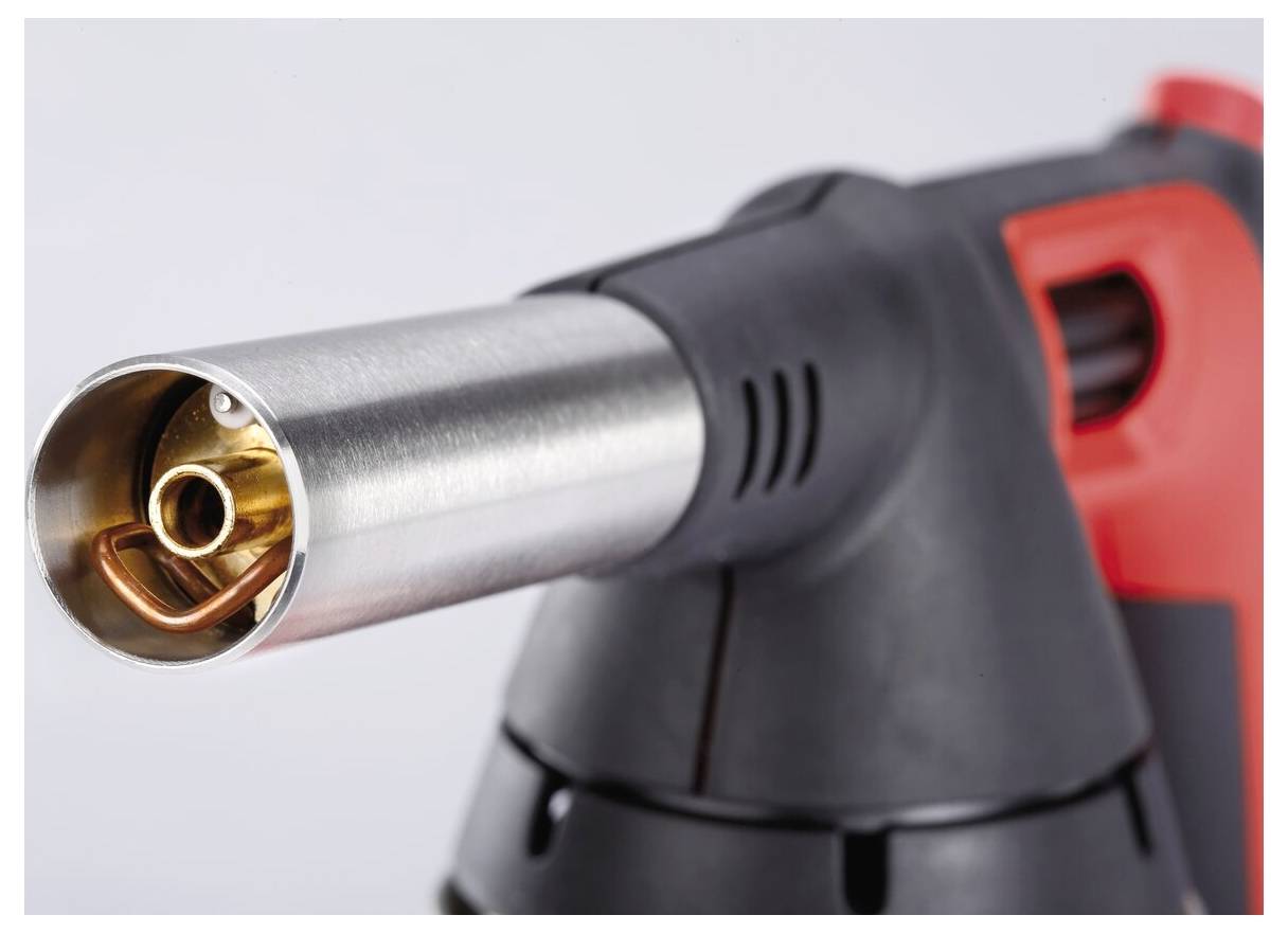„Nahaufnahme eines Gasbrenners mit einer Metalldüse, mit orangefarbenem und schwarzem Griff, mit Fokus auf den Zündungsbereich.