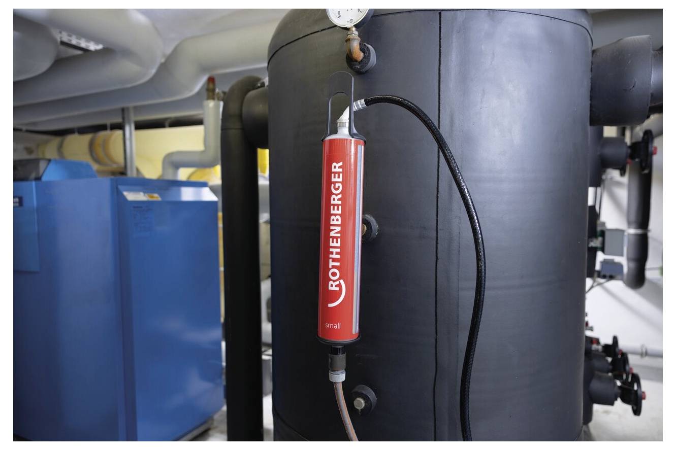 Ein rotes Rothenberger-Gerät, das an einem großen industriellen Tank mit Rohrleitungen in einem Maschinenraum angebracht ist und auf eine Wartungs- oder Überwachungsaktivität hinweist.