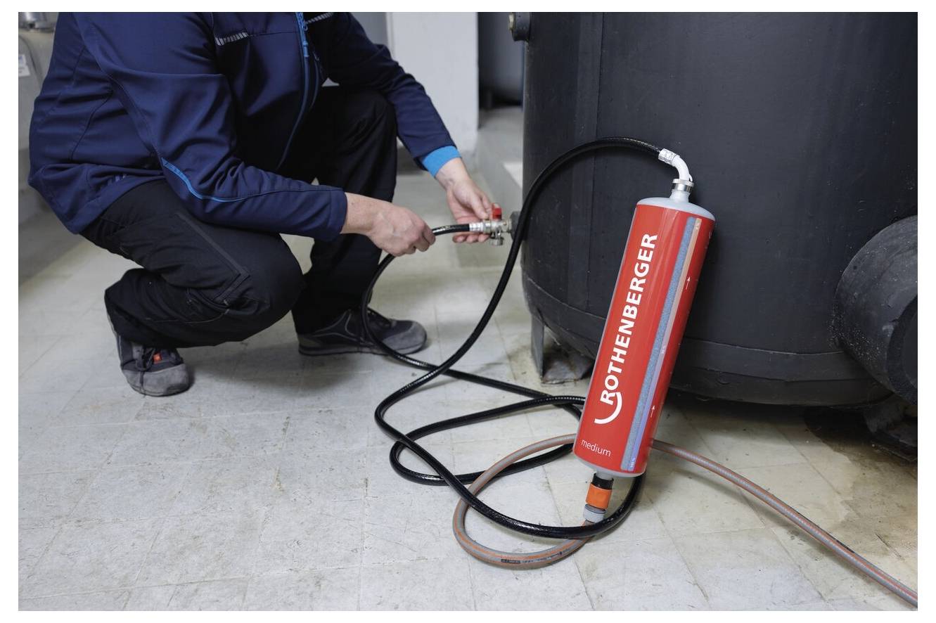 Eine Person verwendet eine Rothenberger-Druckprüfpumpe, die an einen großen Zylinder angeschlossen ist, was auf Gerätewartung oder -prüfung hindeutet.