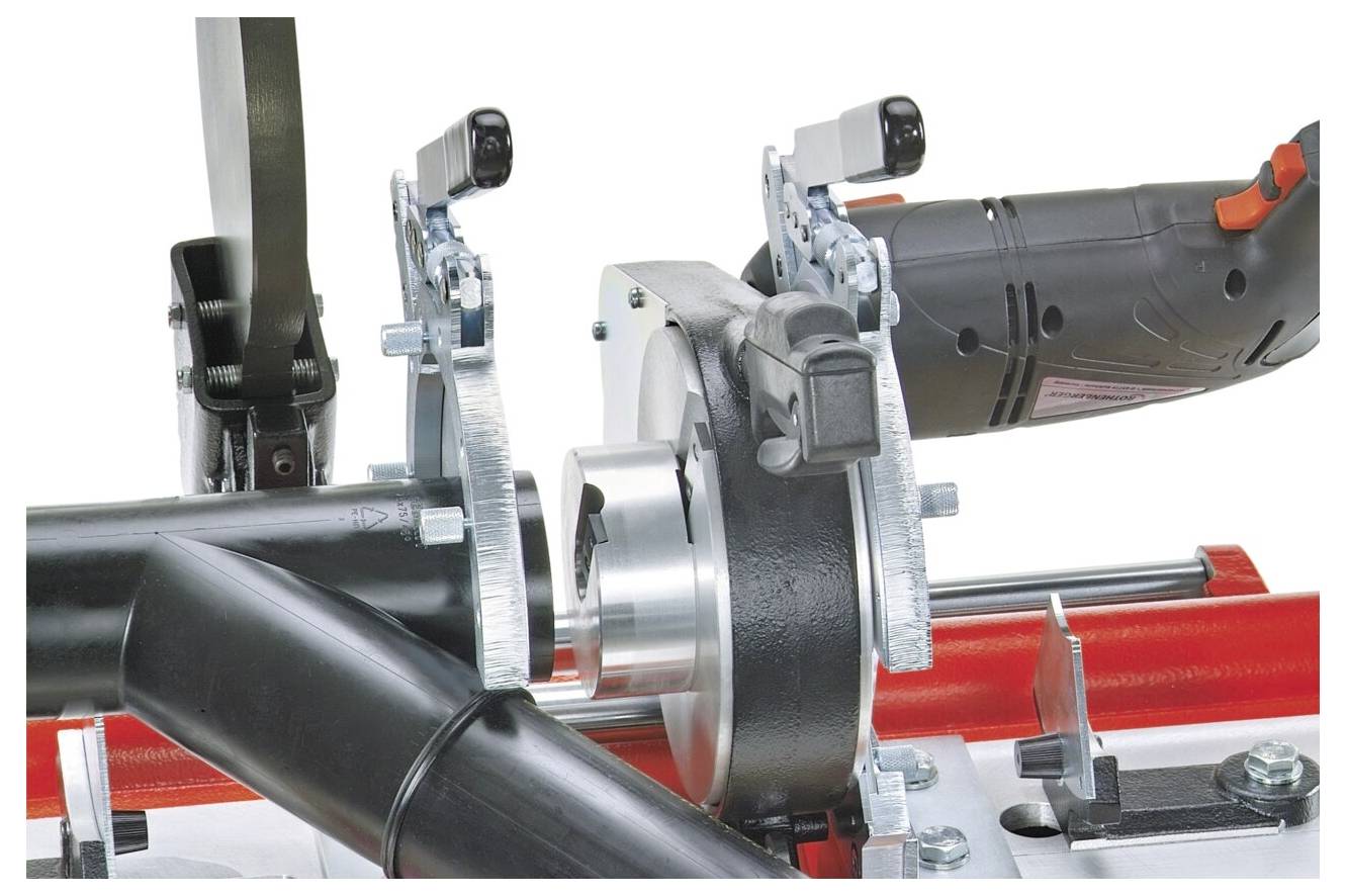 Eine Metallschneidemaschine mit einer kreisförmigen Klinge ist so positioniert, dass sie ein schwarzes Rohr schneiden kann. Zwei verstellbare Klammern halten das Rohr sicher fest.