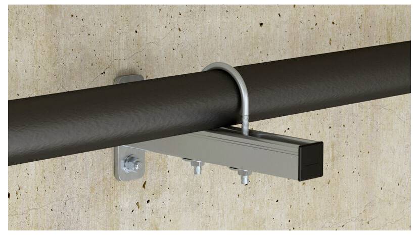 Ein Metallrohr, das mit einer U-förmigen Schelle und einer Metallhalterung an einer Wand befestigt ist und eine sichere industrielle Rohrbefestigungslösung zeigt.
