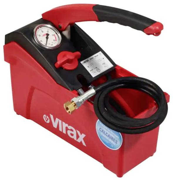 Eine Hand hält ein rotes T-förmiges Handwerkzeug mit einer Metallspitze gegen eine schlichte beigefarbene Wand.