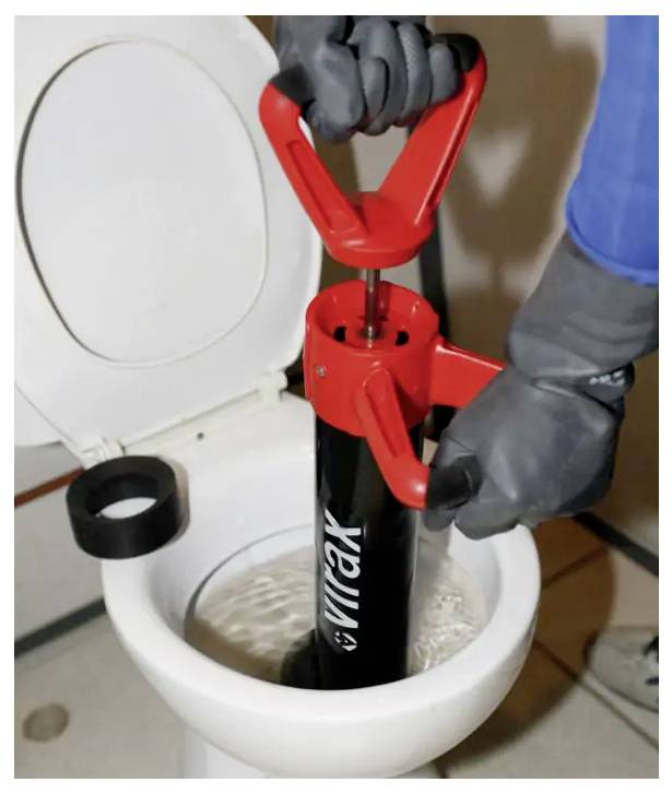 Behandschuhte Hände benutzen einen roten Kolben, um eine Toilette mit offener Brille zu verstopfen.