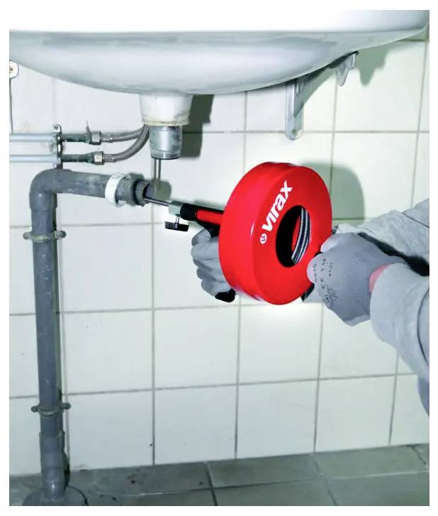 Nahaufnahme von zwei Rohrabsperrventilen auf Kupferinstallation, mit einem Druckmanometer und rotem Griff sichtbar gegen eine Wand.