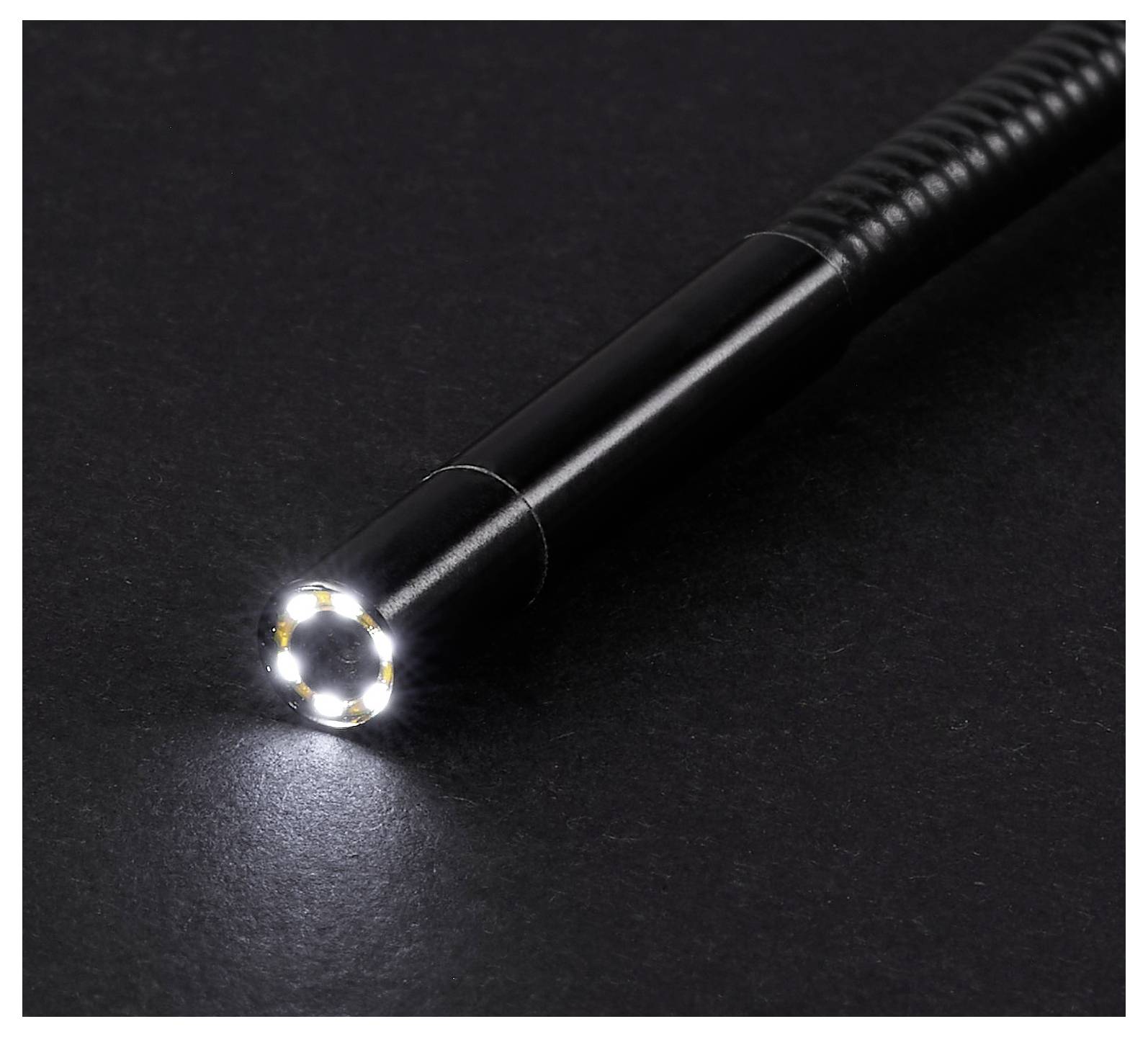 Schwarzische Taschenlampe mit einem hellen LED-Strahl, der auf eine dunkle Oberfläche scheint.
