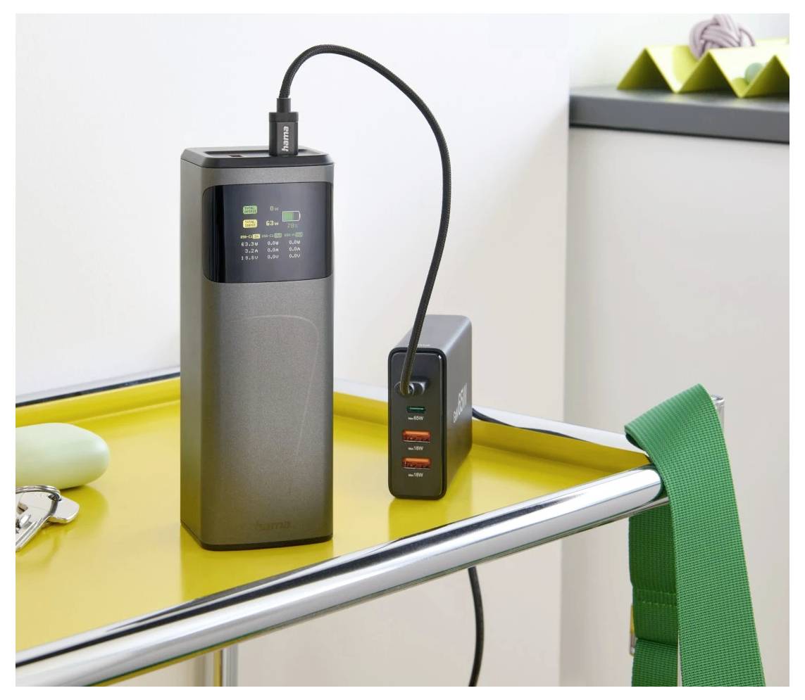 Mehrere Ladegeräte auf einem gelben Tablett; eines ist mit einem Kabel verbunden, mit Etiketten, die den Ladestatus anzeigen.