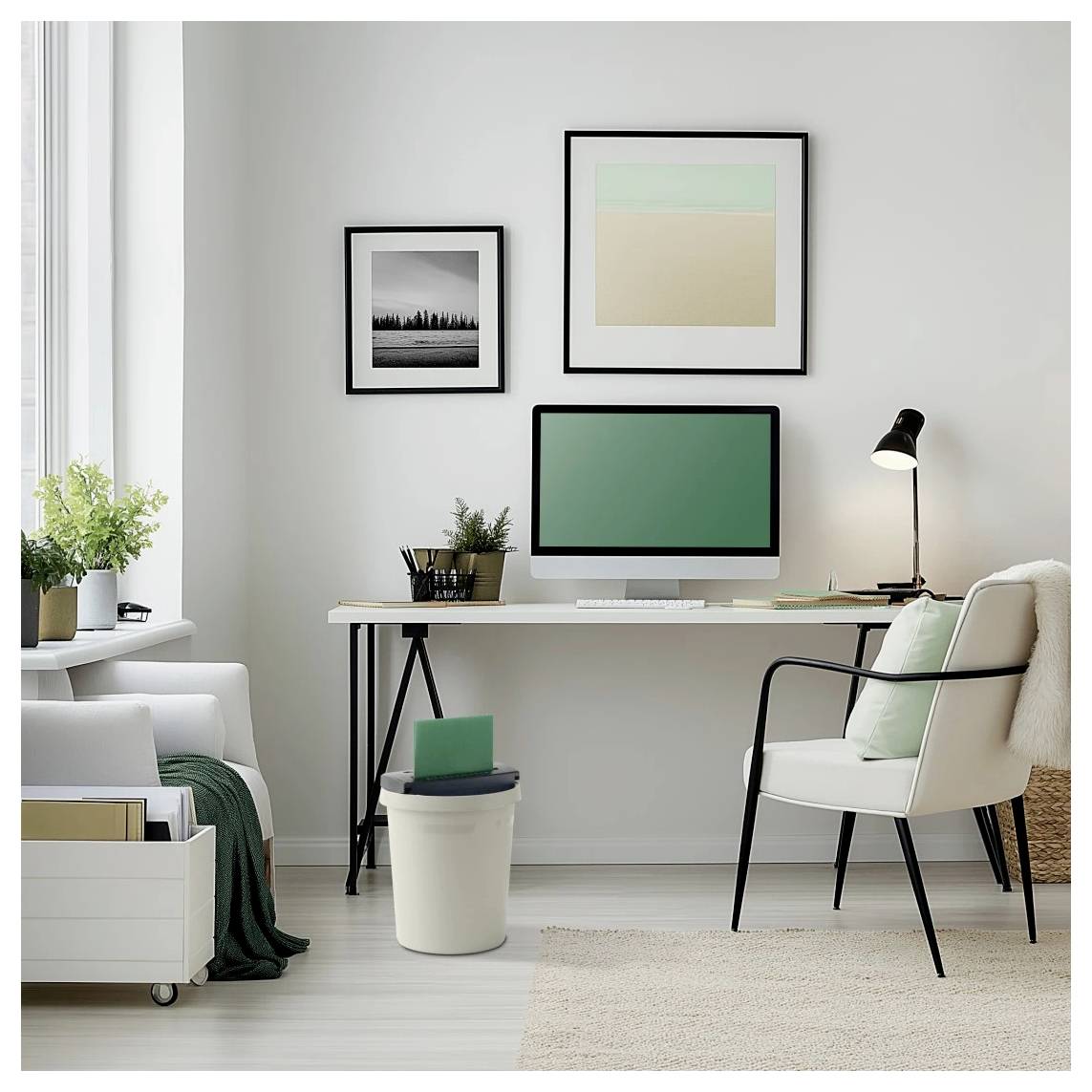 Ein modernes Home Office mit einem Schreibtisch, Computer und grünem Stuhl. Zwei Kunstwerke hängen an der Wand, mit einer Lampe und einer Pflanze auf dem Schreibtisch.