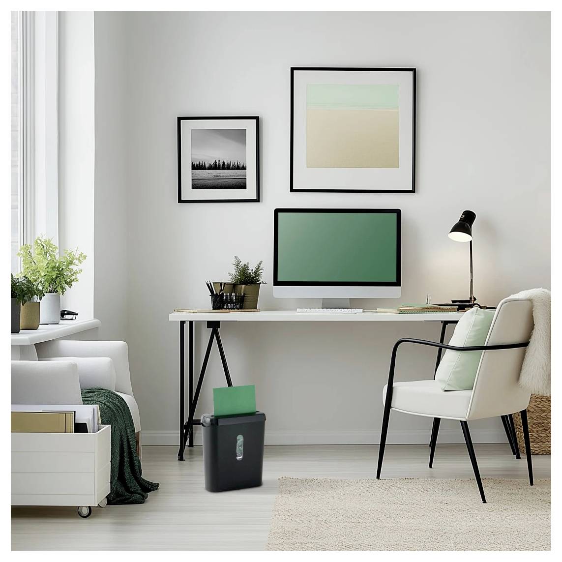 Ein minimalistisches Home Office mit einem Schreibtisch, Computer, Stuhl und Wandkunst. Eine Topfpflanze steht auf dem Schreibtisch, und ein Aktenvernichter befindet sich darunter.