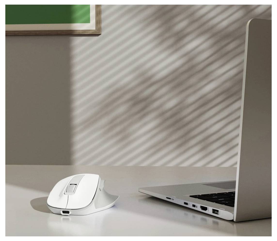 Eine weiße Computermaus liegt auf einem Schreibtisch neben einem offenen Laptop, während Sonnenlicht gestreifte Schatten an der Wand im Hintergrund wirft.