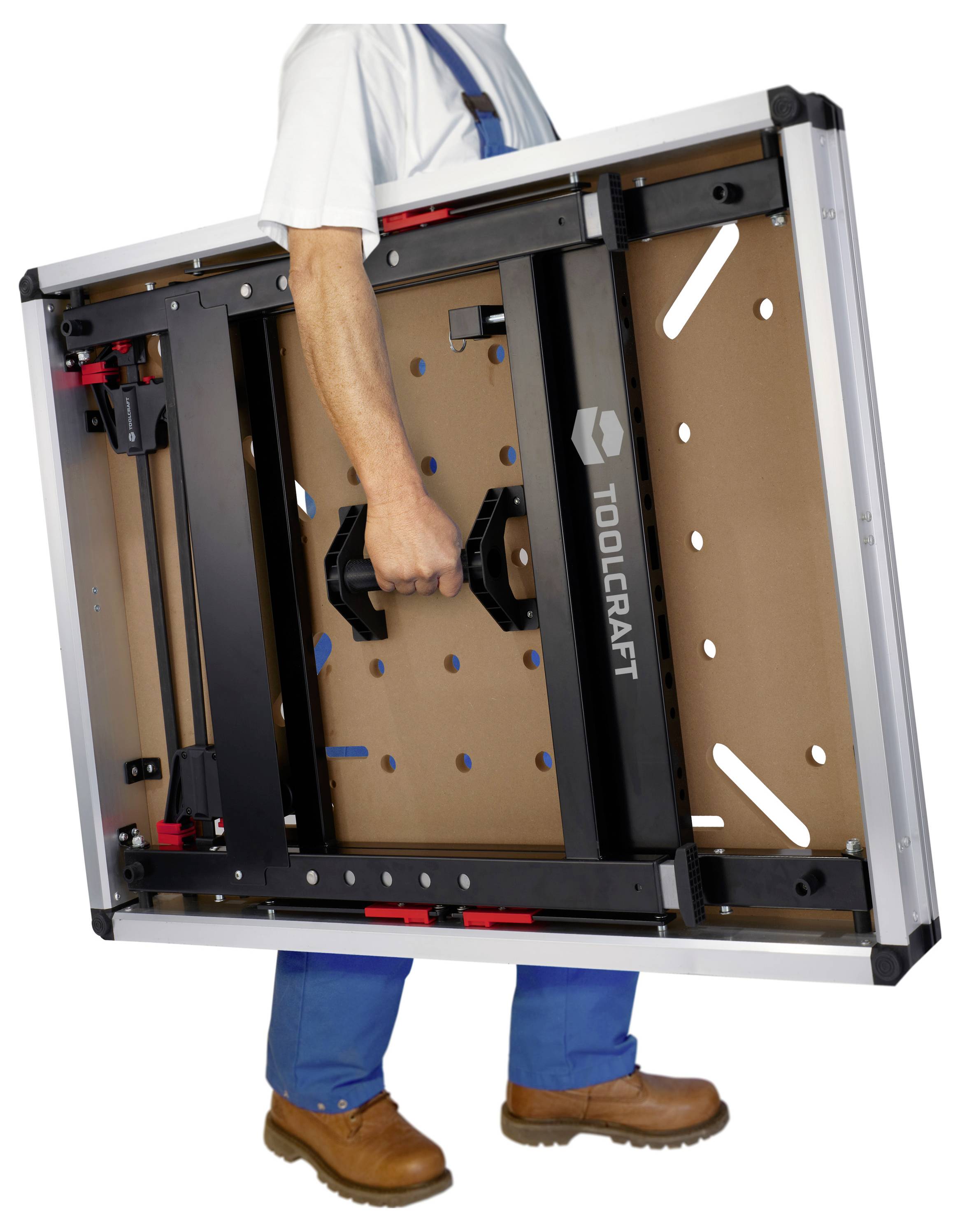 Person trägt eine zusammengeklappte Toolcraft-Werkbank an ihrem zentralen Griff und zeigt dabei das kompakte tragbare Gestell.
