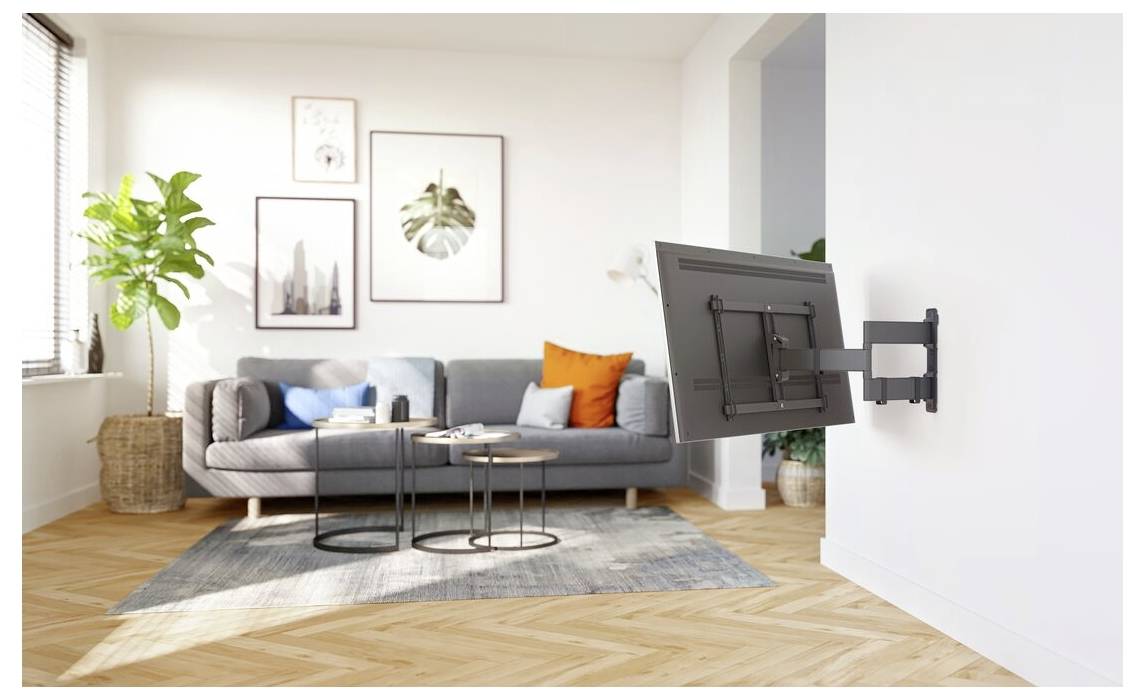 Wandhalterung für Fernseher im Wohnzimmer. Graues Sofa, runde Tische und eine Pflanze in moderner Dekoration. Sonnenlicht durch das Fenster beleuchtet Kunstwerke an der Wand.