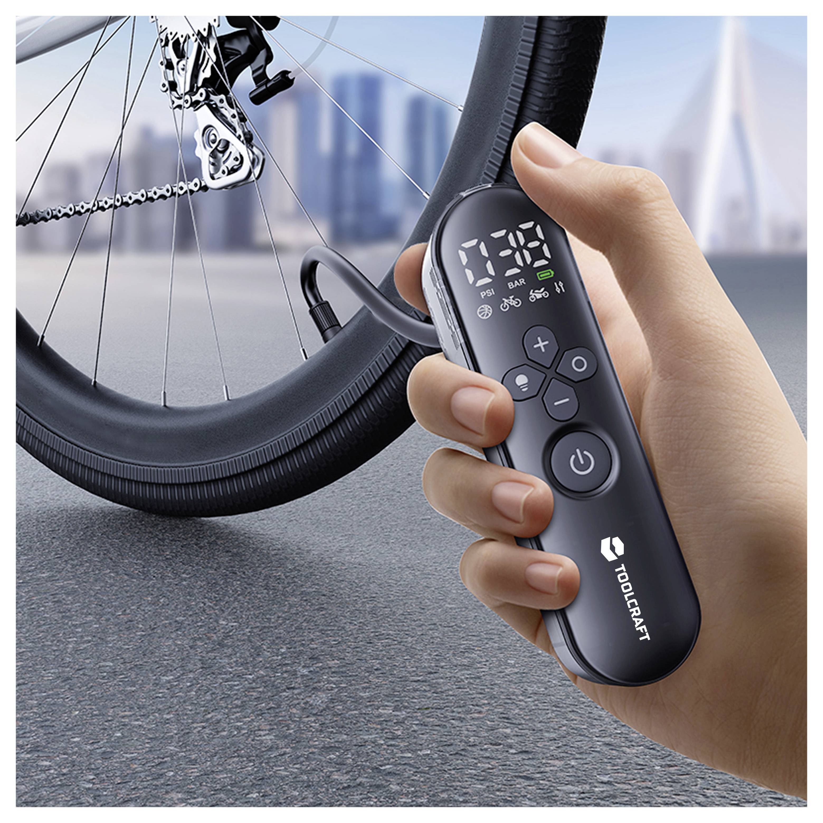 Hand, die eine TOOPCRAFT Elektrofahradpumpe mit digitaler Druckanzeige neben einem Fahrradreifen und Ventil hält.