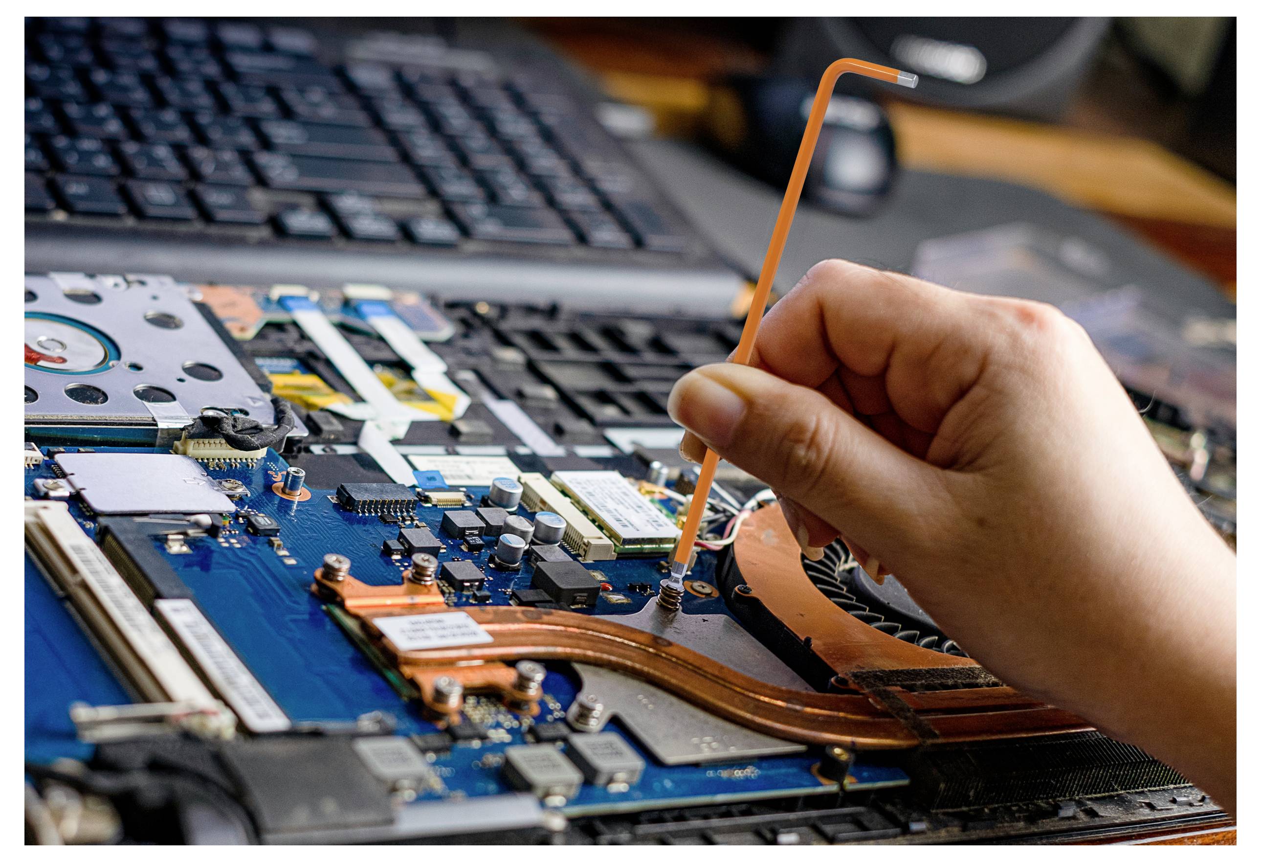 Eine Person, die ein Werkzeug verwendet, um Komponenten auf einem offenen Laptop-Motherboard anzupassen, wobei der Fokus auf Hardwarereparatur oder -aufrüstung liegt.