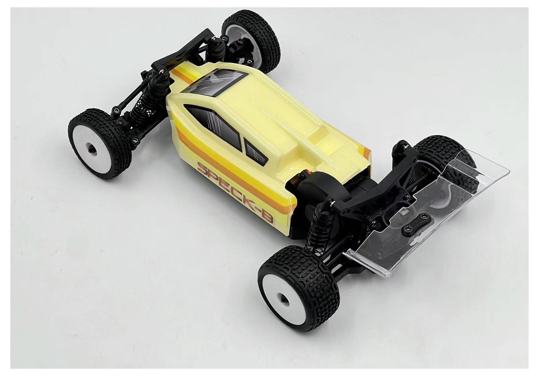 Ein gelbes und weißes ferngesteuertes Auto mit schwarzen Rädern wird auf einer einfarbigen weißen Oberfläche platziert. Das Auto verfügt über ein schlankes, aerodynamisches Design.