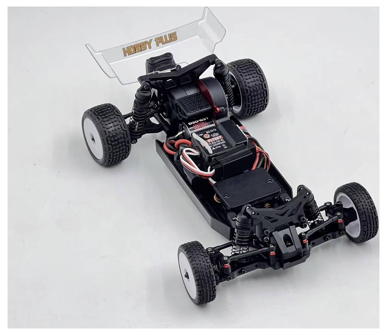 Ein schwarzes ferngesteuertes Autochassis mit sichtbaren Elektronikkomponenten und Kabeln, das die internen Bauteile und Struktur auf einem hellen Hintergrund präsentiert.