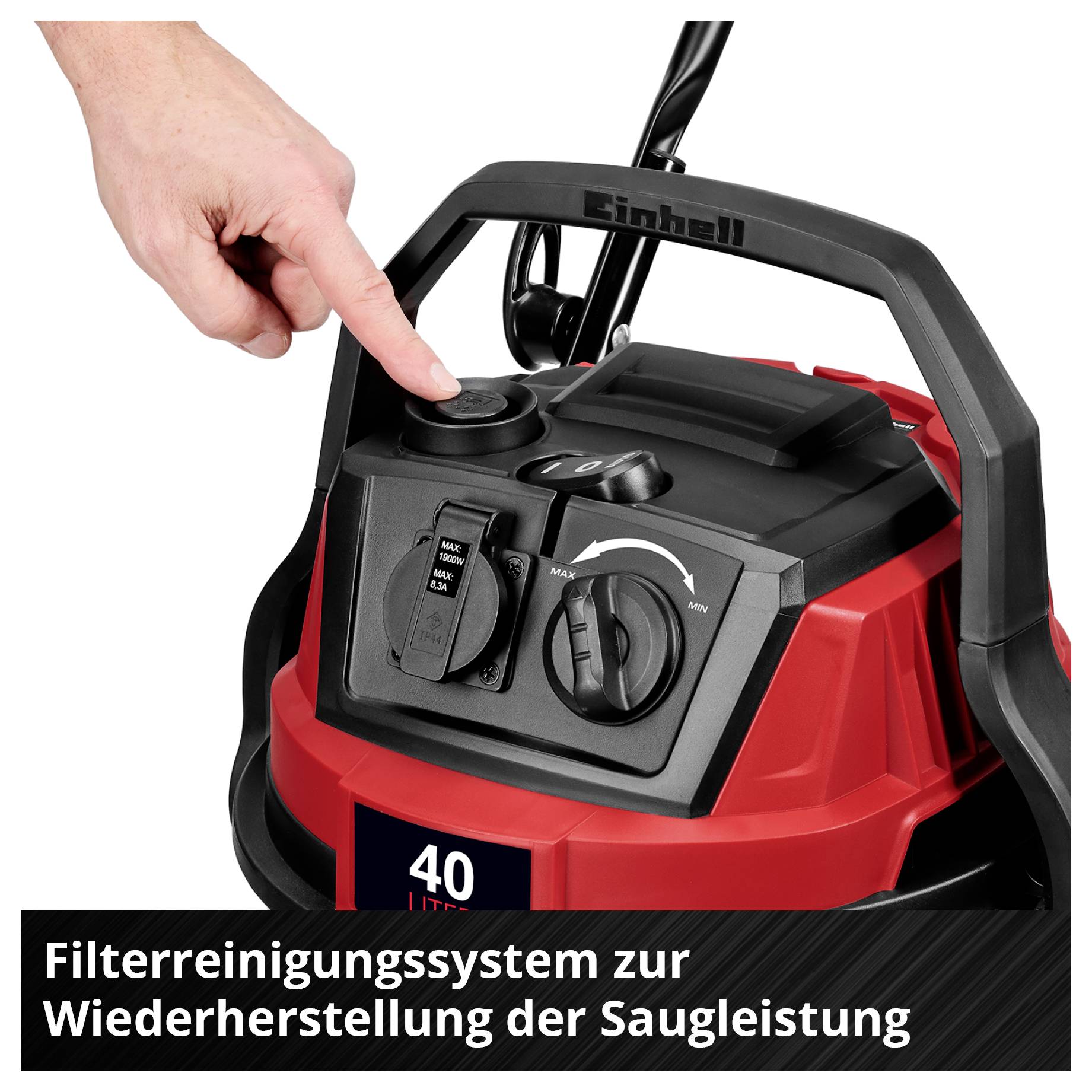Die Hand zeigt auf die Bedienelemente eines rot-schwarzen Staubsaugers mit der Aufschrift 'Filterreinigungssystem zur Wiederherstellung der Saugleistung'.
