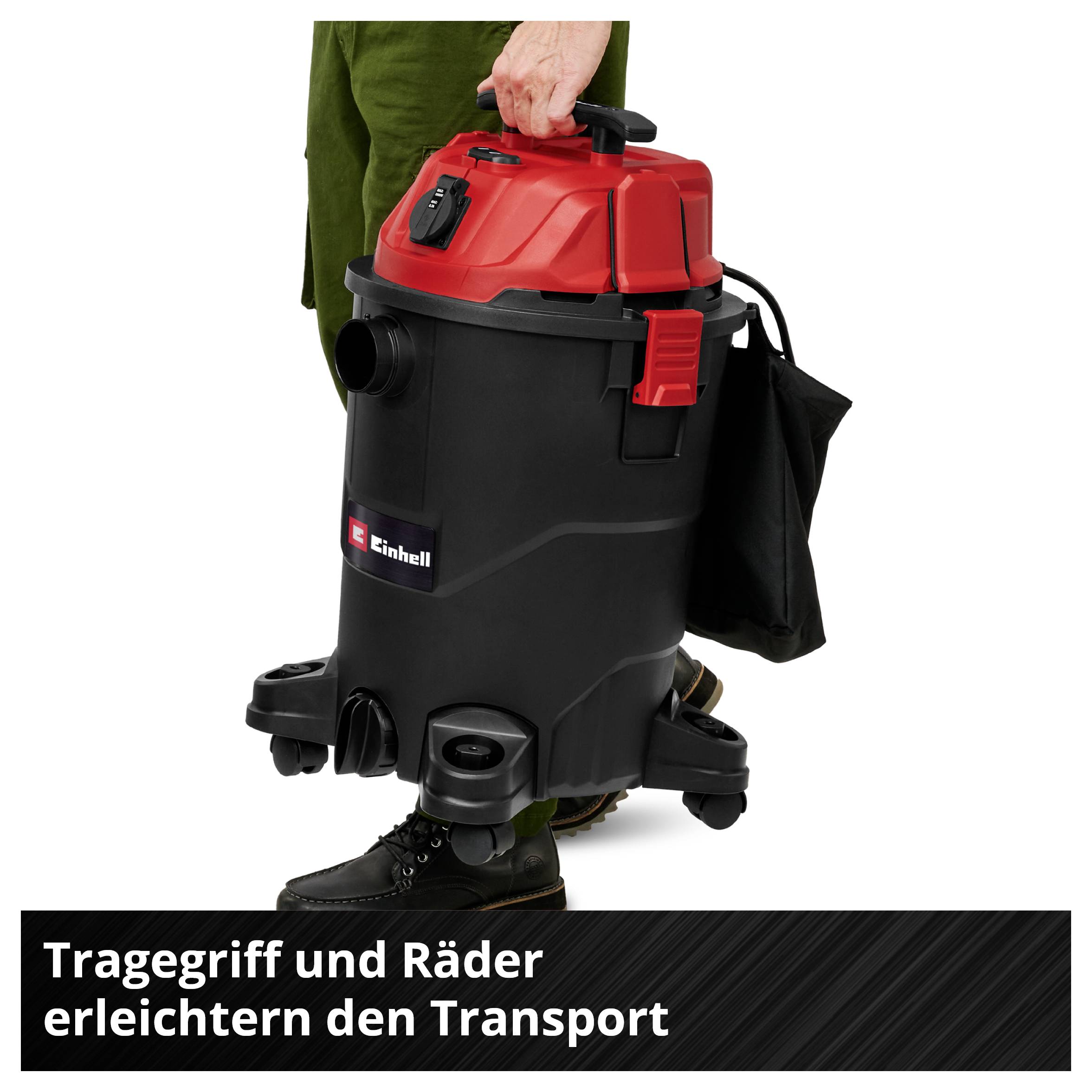 Ein roter und schwarzer Staubsauger mit Tragegriff und Rädern wird transportiert. Text: 'Tragegriff und Räder erleichtern den Transport'.