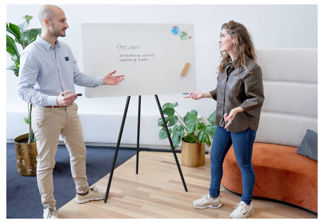 Zwei Personen führen eine Diskussion an einem Whiteboard, auf dem die 