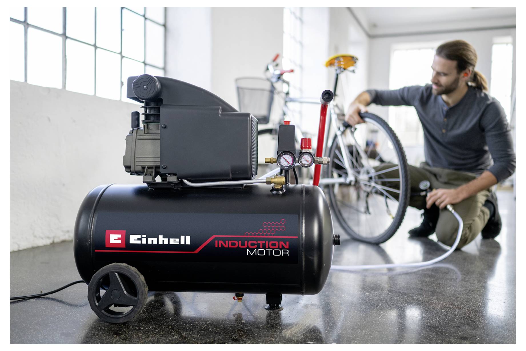 Eine Person pumpt einen Fahrradreifen mit einem Luftkompressor der Marke 