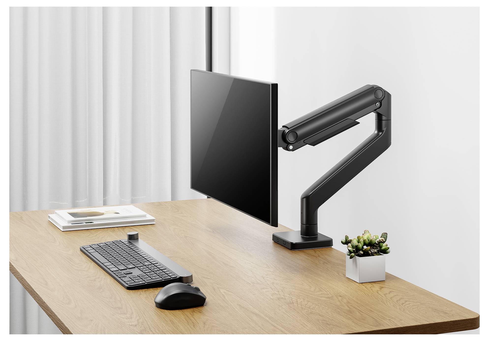 Ein Computermonitor auf einem verstellbaren Arm, auf einem Holzschreibtisch neben einer Tastatur, einer Maus und einer kleinen Topfpflanze platziert.