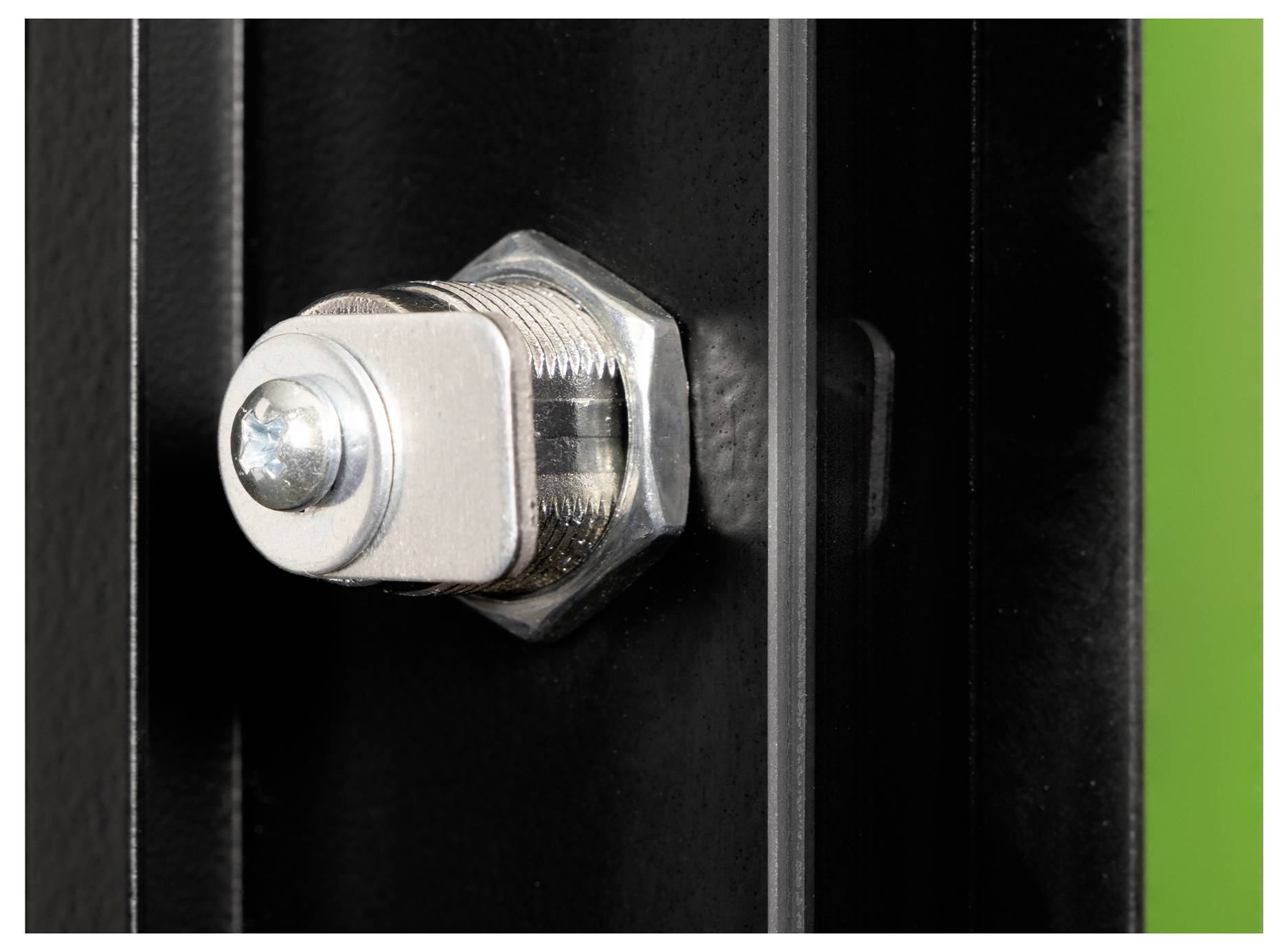 Nahaufnahme einer metallischen Schraube, die durch ein schwarzes Blech mit grünem Hintergrund auf der rechten Seite befestigt ist und ein Hardware-Detail zeigt.