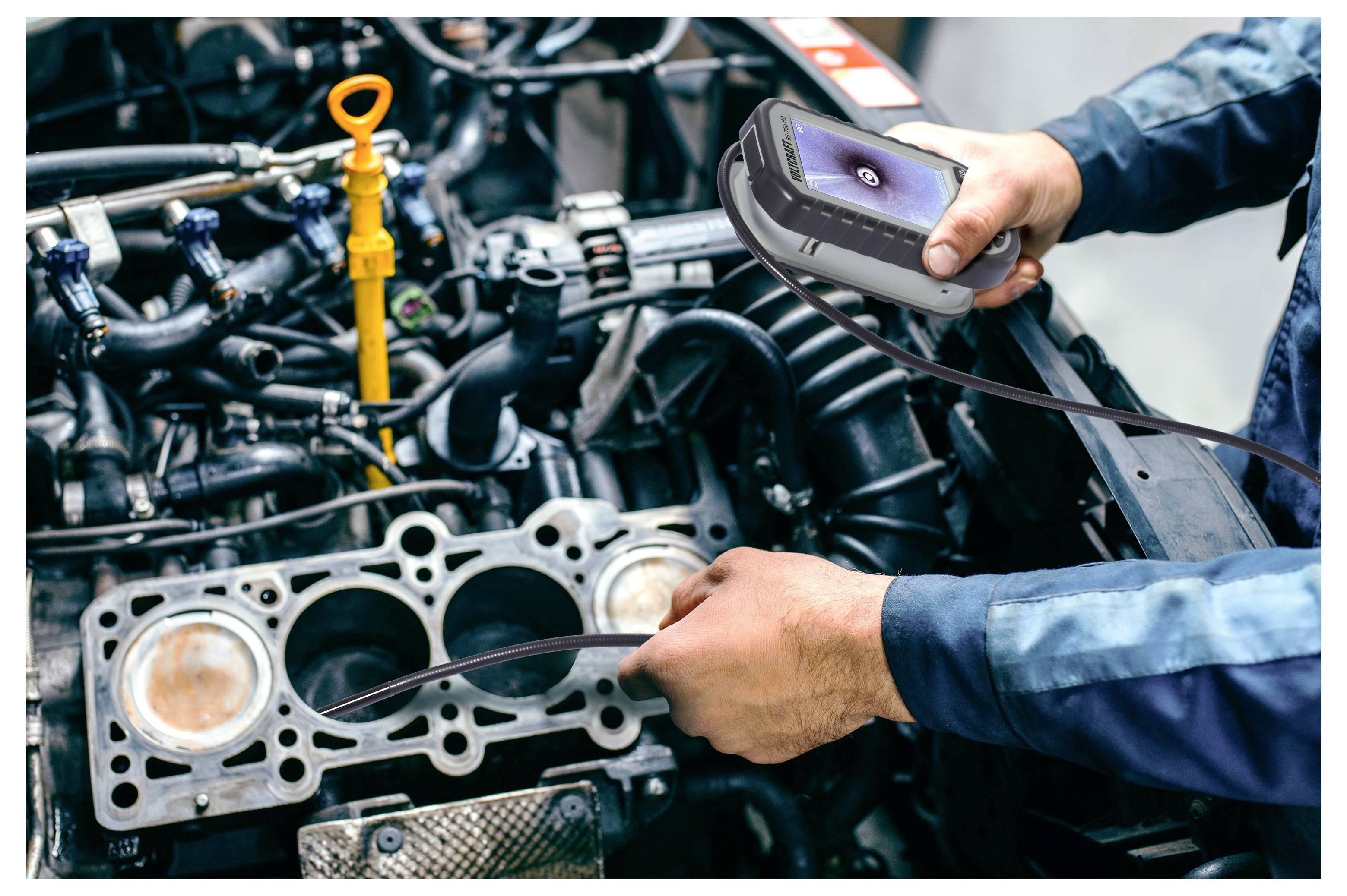 Mechaniker benutzt eine tragbare Inspektionskamera, um einen Automotor mit entferntem Zylinderkopf zu untersuchen und interne Komponenten zu überprüfen.
