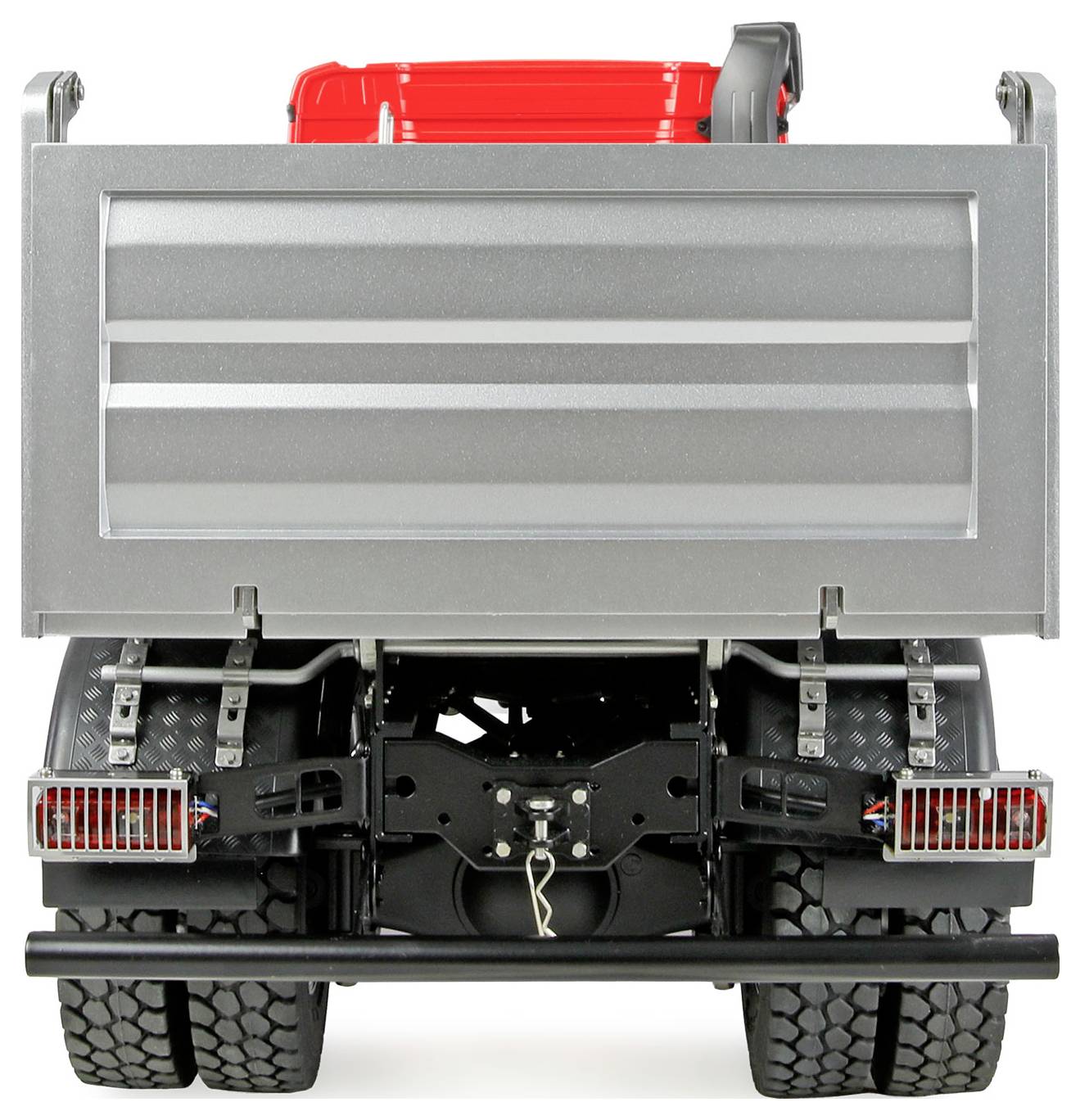 Ein Spielzeug-Kipplaster, von hinten betrachtet, mit einer roten Fahrerkabine, großen schwarzen Rädern und einer silbernen Ladepritsche.