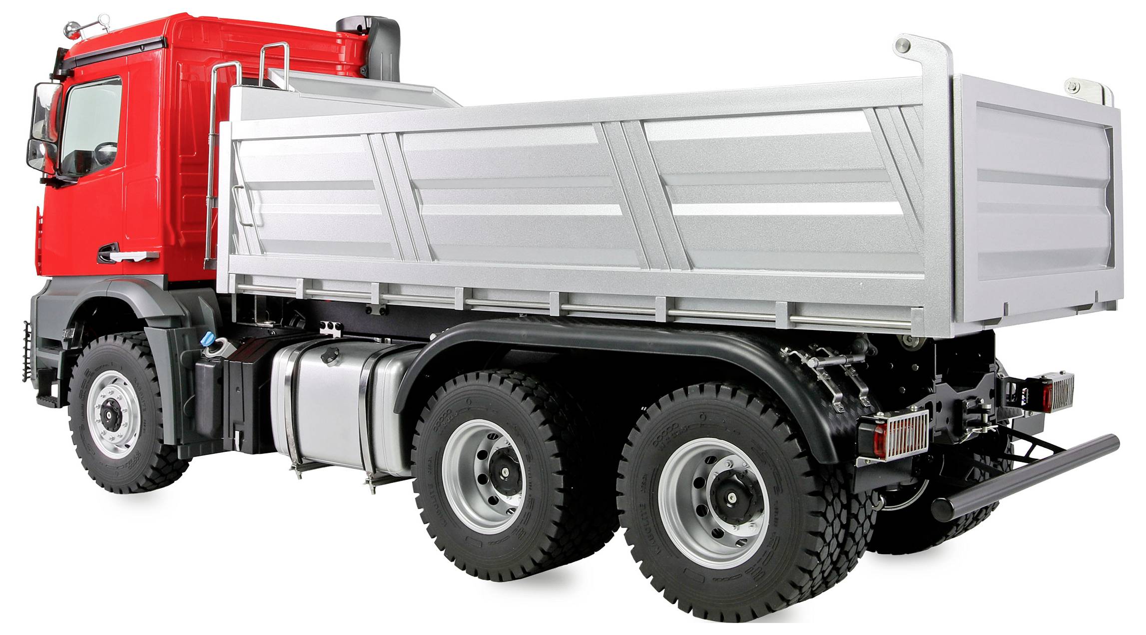 Ein großer roter und silberner Kipplaster mit sechs Rädern, ausgestattet mit einer Ladefläche aus Metall und sichtbarem Auspuffsystem, von der Rückseite betrachtet.