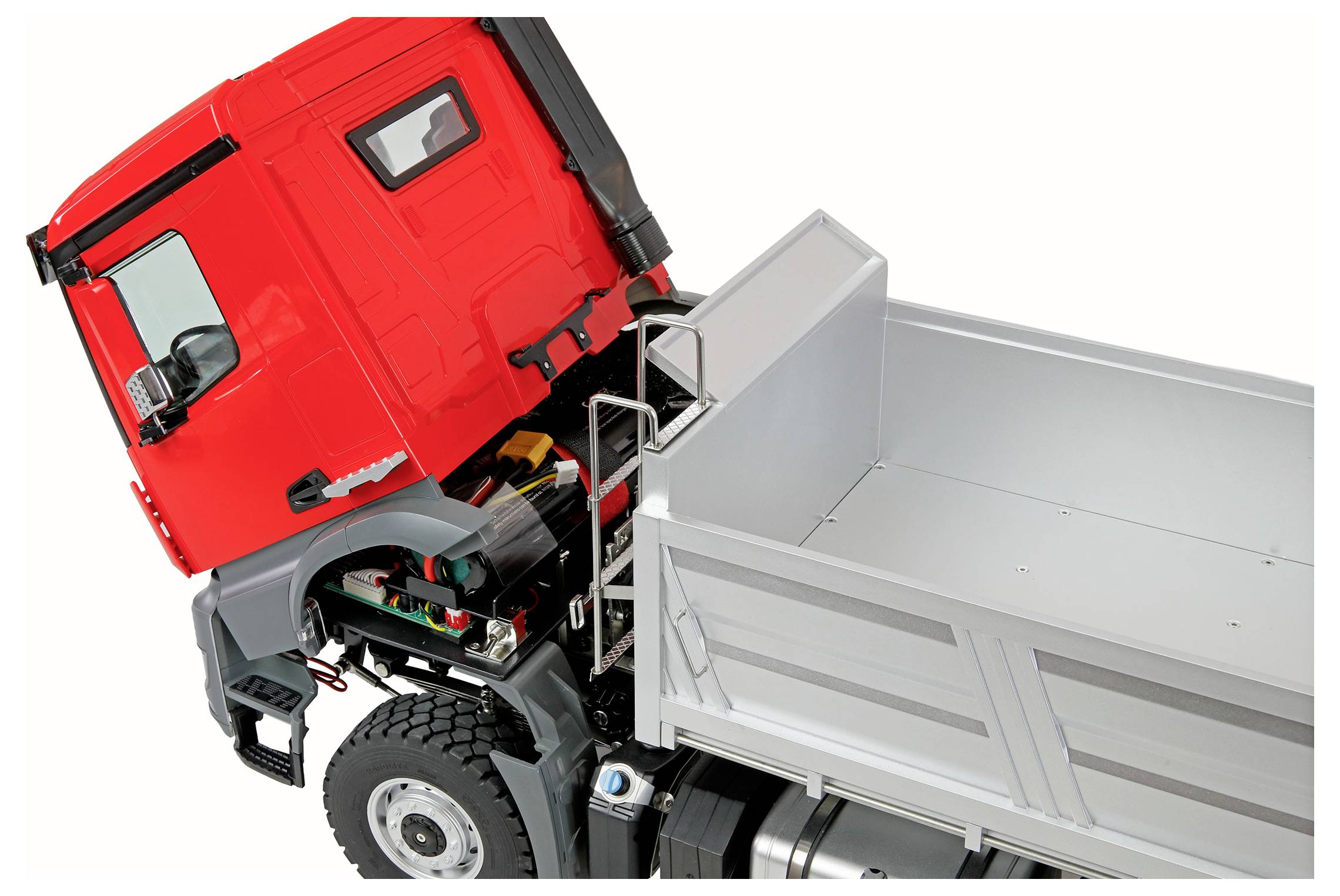 Ein hellroter Lastwagen mit offener Motorhaube gibt Einblick in seine inneren mechanischen Komponenten, neben einer leeren silbernen Ladefläche, aus einem Winkel betrachtet.