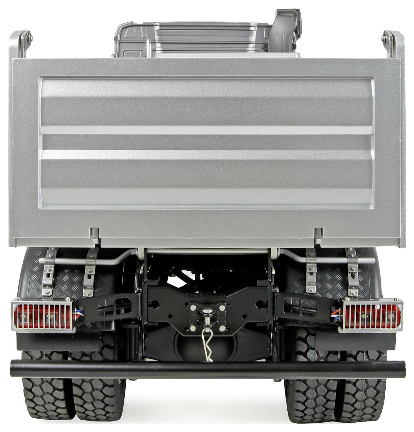 Ein großer silberner Kipplaster, von hinten gesehen, mit strukturierten Metallpaneelen und robusten Reifen, was auf industrielle Nutzung oder Bauarbeiten hindeutet.