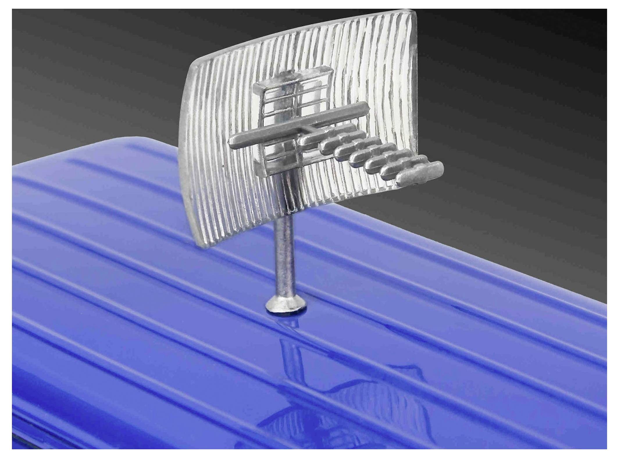 Eine blaue Metalloberfläche mit einem silbernen, strukturierten segelbootähnlichen Ornament darauf montiert.