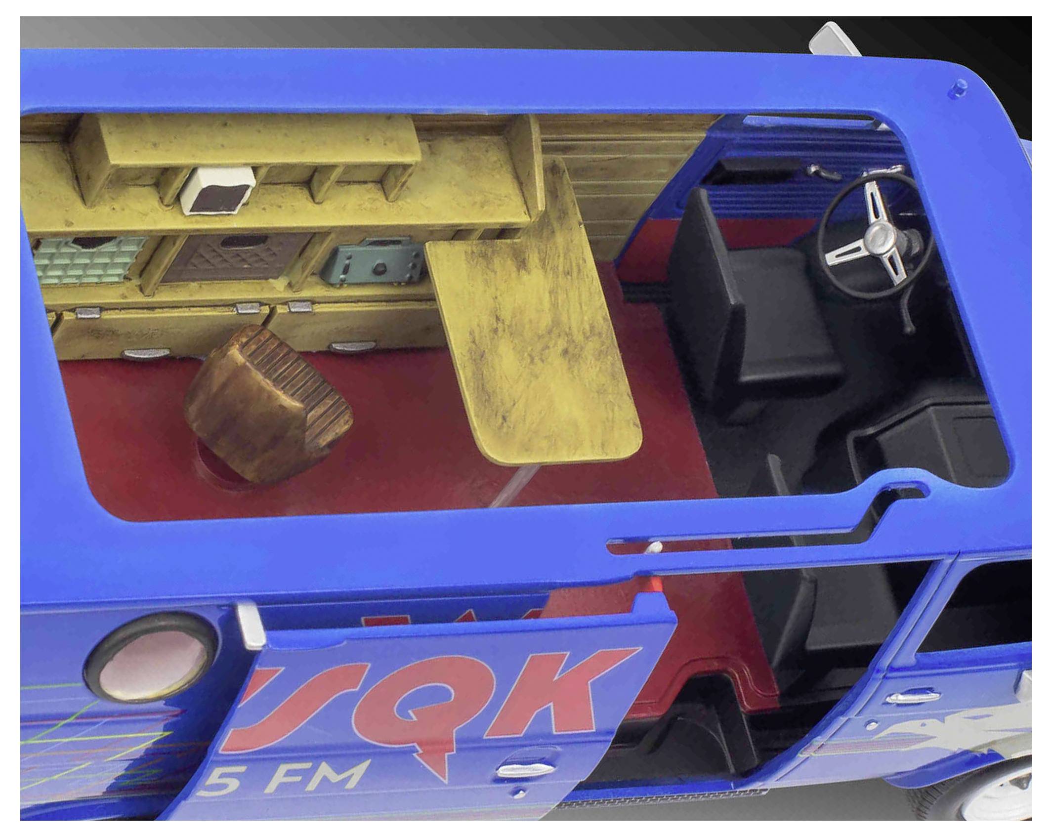 Draufsicht des Innenraums eines Lieferwagens mit einem Holztisch und einem Stuhl im Heckbereich sowie einem Fahrersitz mit Lenkrad in der vorderen Kabine.